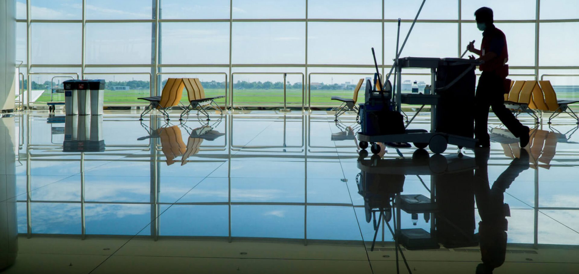 E&E Reinigungsmitarbeiter schiebt einen Wagen über den gläsernen Boden in einem Flughafen.